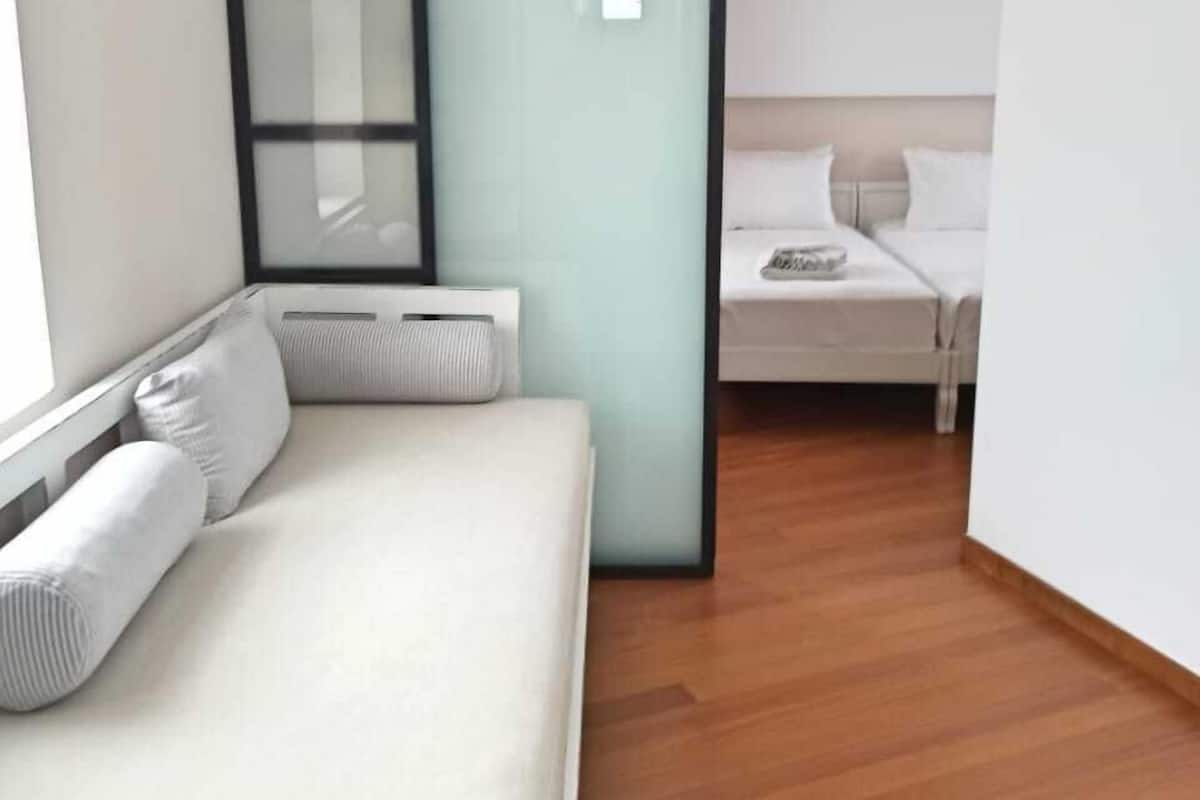 A modern bedroom with a bed, a window, and a sliding door leading to another room.