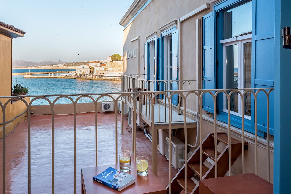 A balcony with a view of the sea, a table with a book and glasses, and a staircase.