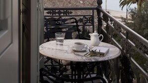 A balcony with a table set for two, a white pitcher, a cup, and a book. - Ippoliti Hotel (Nafplio)