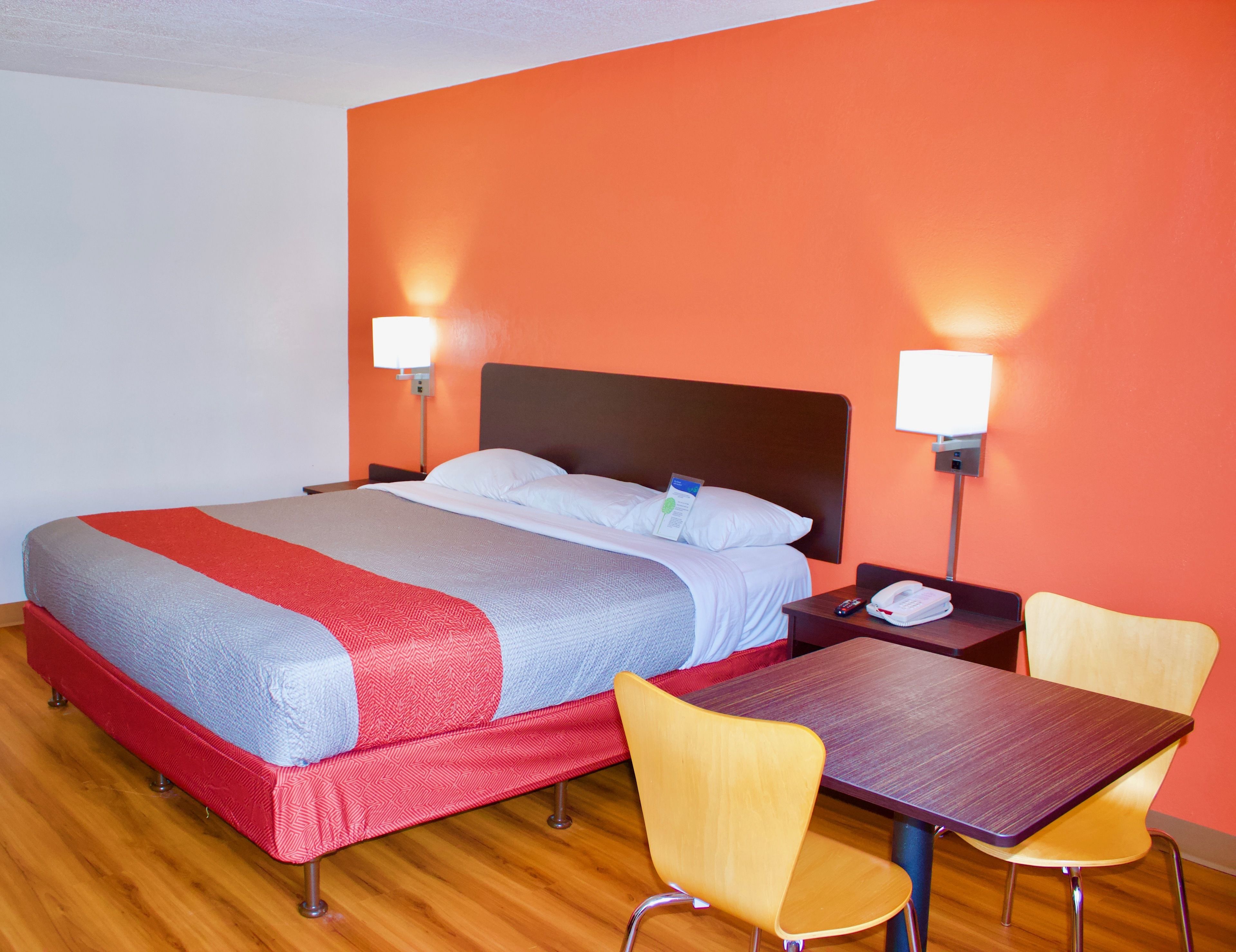 A hotel room with a bed, bedside tables, a desk, and two chairs.