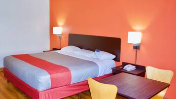 A hotel room with a bed, bedside tables, a desk, and two chairs.