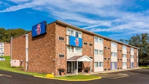 A brick motel with a blue sign, a covered entrance, and a parking lot. - Motel 6 New Stanton, PA (New Stanton)