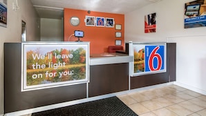 A reception desk with a sign that reads "We'll leave the light on for you." - Motel 6 New Stanton, PA (New Stanton)