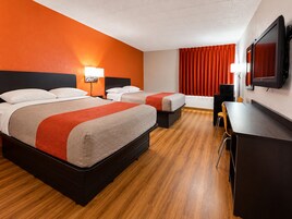 Habitación de hotel con dos camas, un escritorio, una silla, un televisor y una ventana con cortinas.
