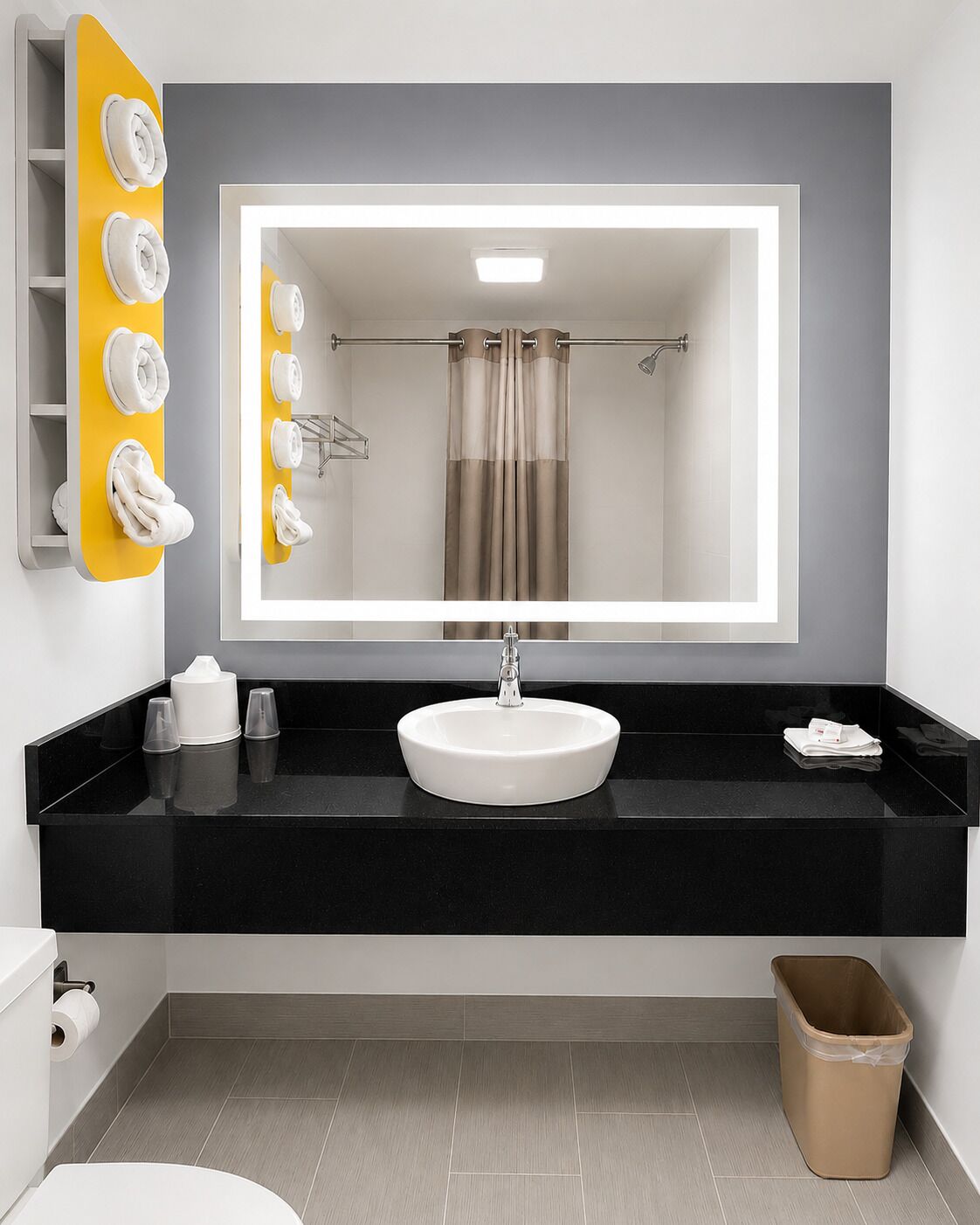 A bathroom with a large mirror, a white sink, and a towel rack with towels.