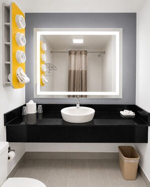 A bathroom with a large mirror, a white sink, and a towel rack with towels. - Motel 6 New Stanton, PA (New Stanton)