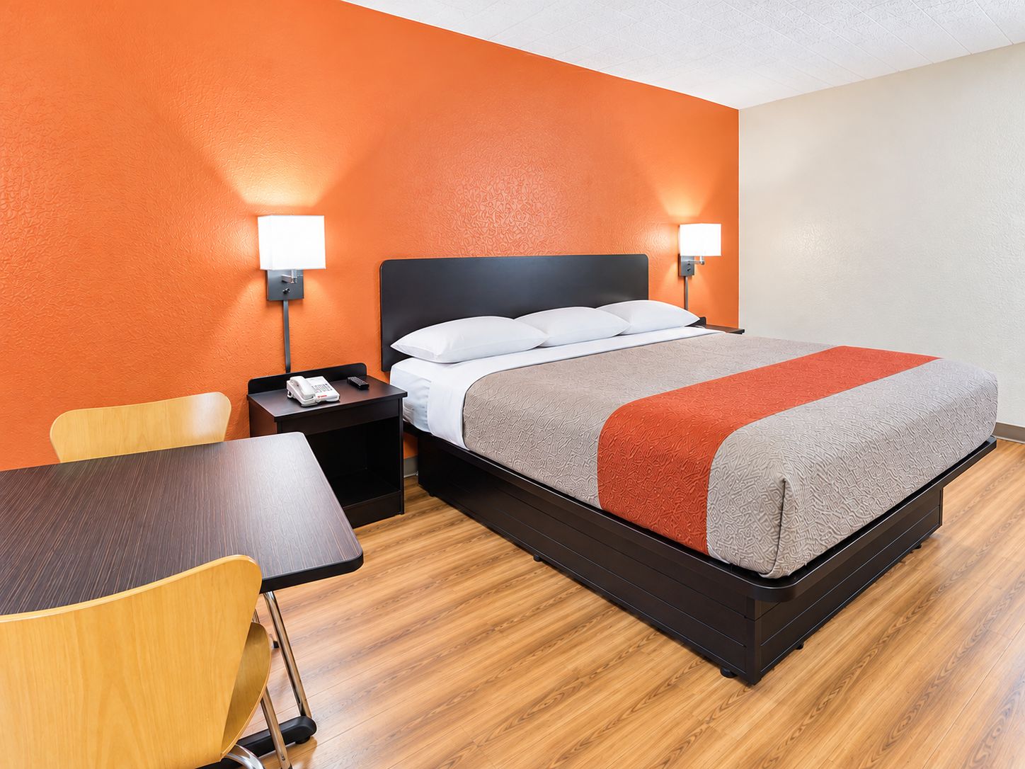 Una camera d'albergo con un letto, comodini, una sedia e una scrivania.