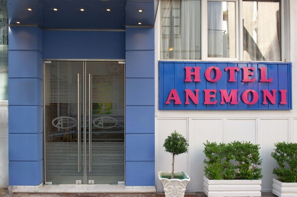 A hotel entrance with a blue facade, a glass door, and a sign reading "HOTEL ANEMONI". - Anemoni (Piraeus)