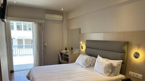 A hotel room with a bed, bedside table, and a desk with a mirror. - Anemoni (Piraeus)