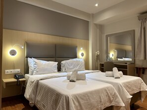Habitació d'hotel amb dos llits, una taula de treball, una cadira, un mirall i un telèfon al taulell.