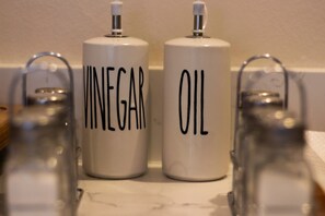 Two white containers labeled 'VINEGAR' and 'OIL' on a countertop. - Anemoni (Piraeus)