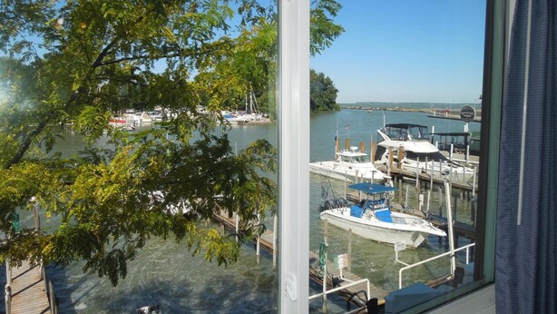 Une vue d’une marina avec des bateaux amarrés, un quai en bois et un ciel dégagé.