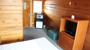A compact room with a bed, a television, a microwave, and a small seating area.