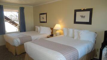 A hotel room with two beds, a ceiling fan, a lamp, and a framed picture on the wall.