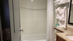 A bathroom with a bathtub, toilet, and a sink with a mirror. - Ramada by Wyndham New York Times Square West (New York)