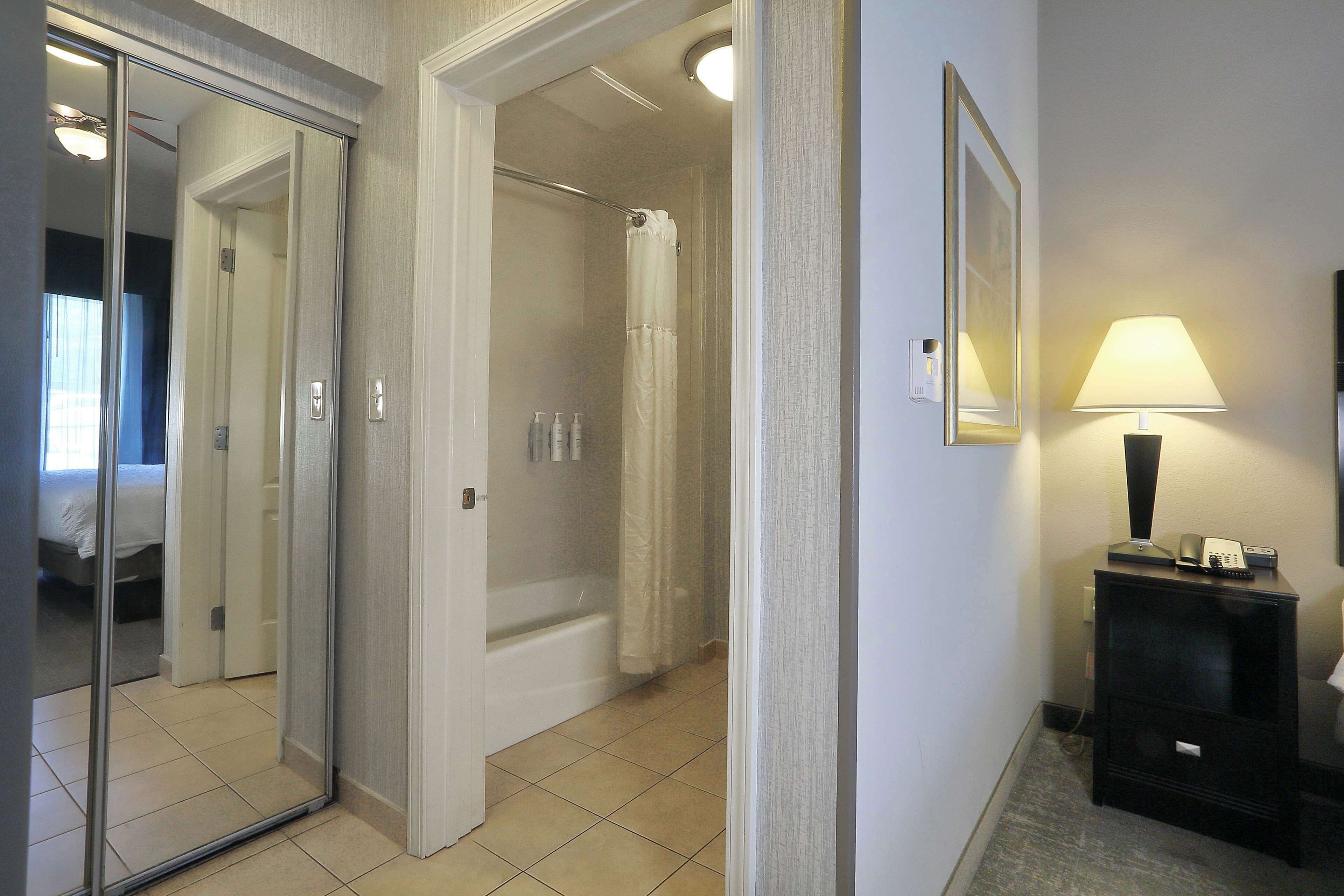 A hotel bathroom with a shower, a bathtub, and a mirror.
