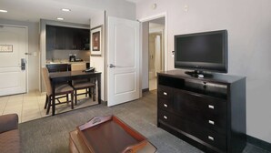 Une chambre d’hôtel comprenant un coin repas, une télévision, une commode et une petite table d’appoint.