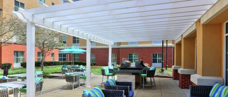A covered outdoor patio with seating, a grill, and a pool area.