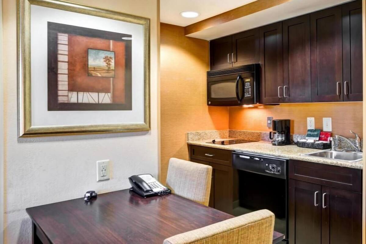 Habitación de hotel con una mesa de comedor, sillas, microondas, cafetera y teléfono.
