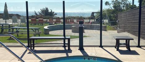 A swimming pool with a view of the ocean, outdoor seating, and a wooden deck.