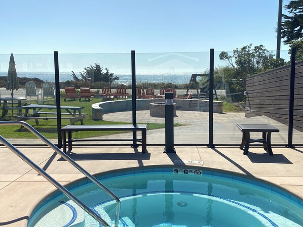 A swimming pool with a view of the ocean, outdoor seating, and a wooden deck.