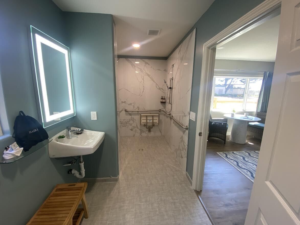 A bathroom with a marble shower, a sink, and a bench.