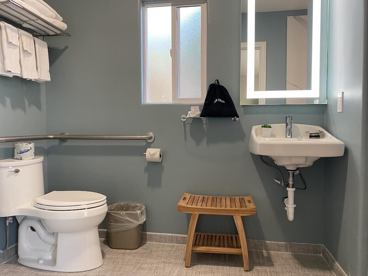 A bathroom with a toilet, sink, and wooden stool.