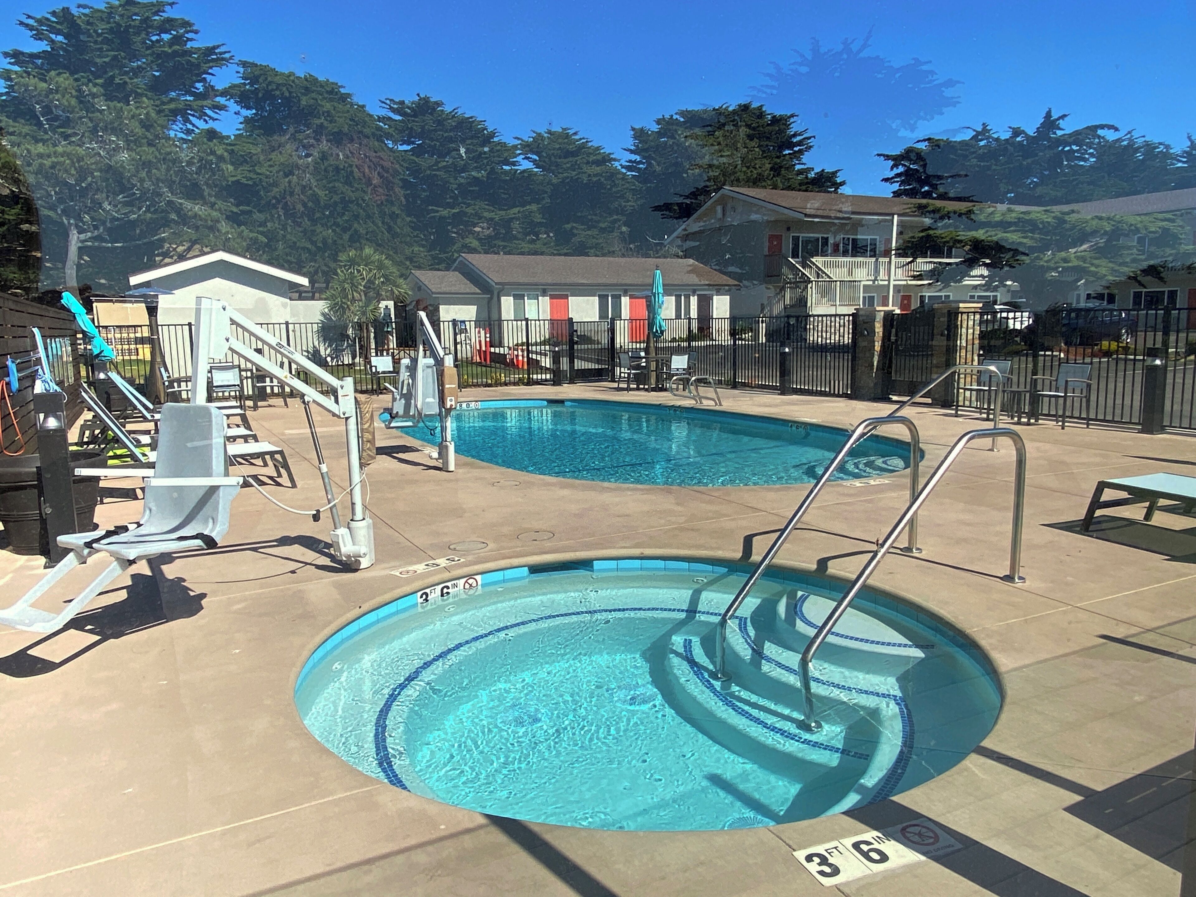 A swimming pool with a 3-foot and 6-inch depth marking, a lifeguard stand, and a small deck area with chairs and a table.