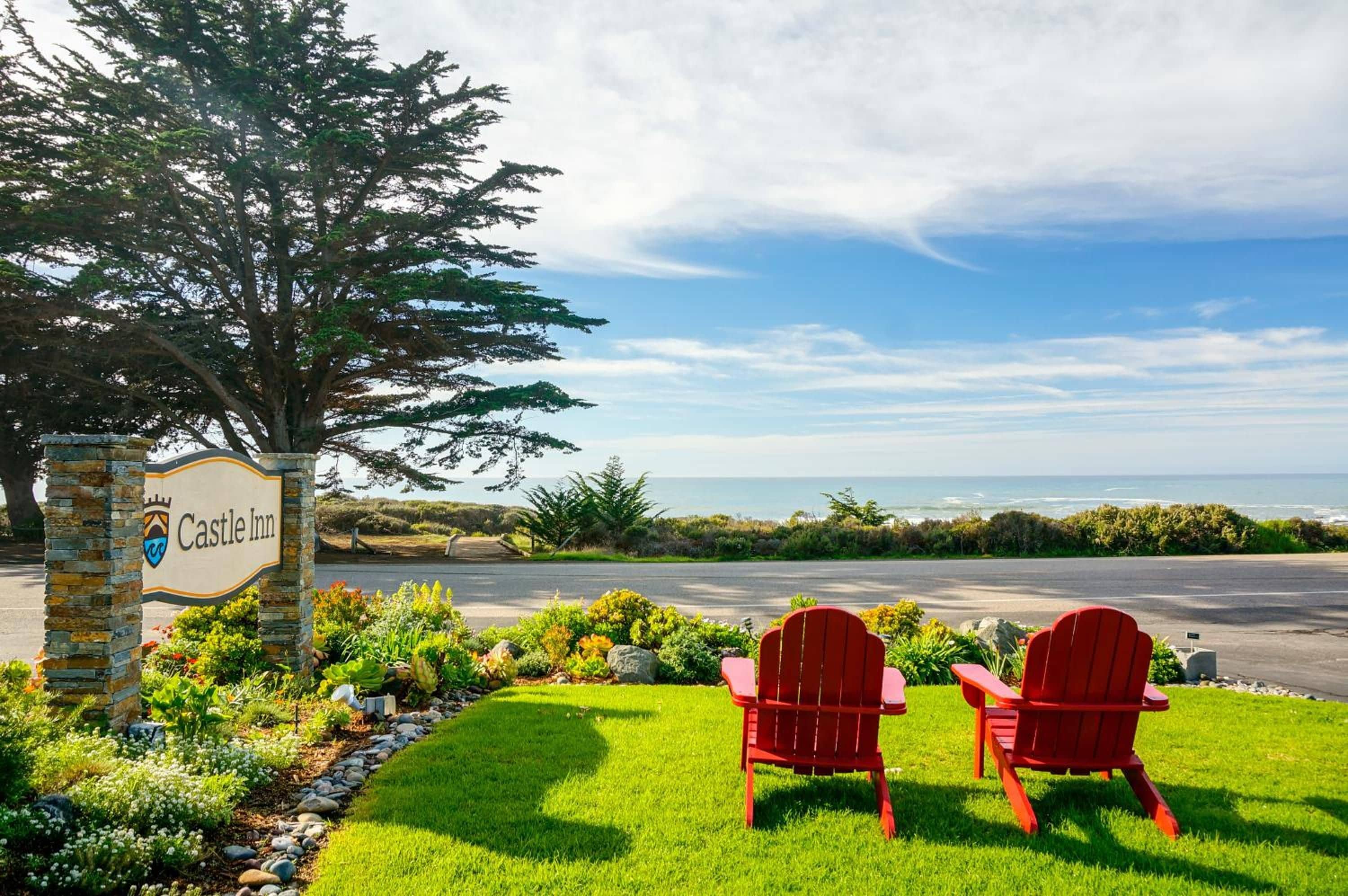 A sign for Castle Inn with a view of the ocean.