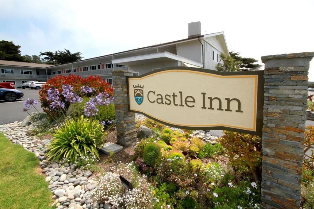 A sign for Castle Inn with a stone wall and landscaped garden.