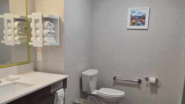 Une salle de bain moderne avec un grand miroir, un lavabo blanc et des toilettes.
