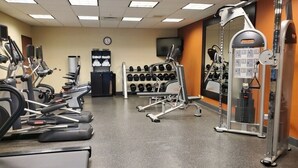 Un gimnasio con cintas de correr, máquinas de pesas y mancuernas.