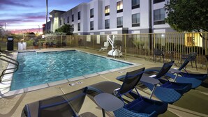 A swimming pool with lounge chairs and a fenced area, surrounded by a modern building with multiple windows. - Hampton Inn & Suites Tucson East/Williams Center (Tucson)