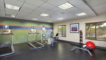 A gym with treadmills, an elliptical, a stationary bike, and a red exercise ball.