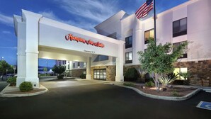 A Hampton Inn & Suites building with a clear sky, an American flag, and a well-lit entrance. - Hampton Inn & Suites Tucson East/Williams Center (Tucson)