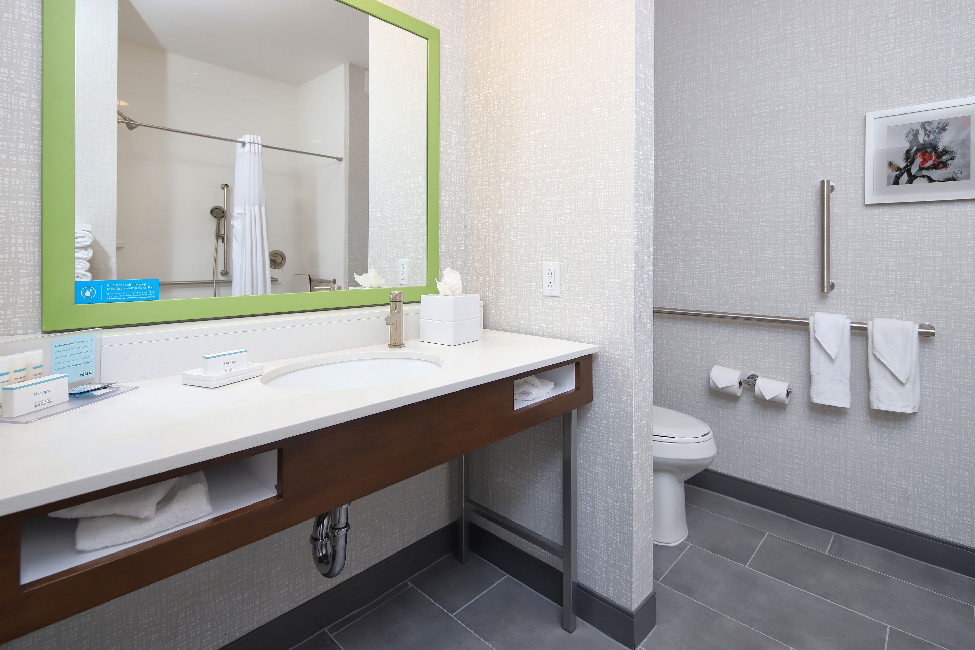 A modern bathroom with a large mirror, white sink, and a toilet.