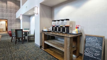 A breakfast area with a coffee station, seating, and a chalkboard menu.