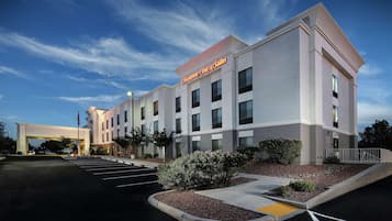 A modern hotel with a flat roof, multiple windows, and a parking lot.