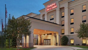 Un hôtel Hampton Inn & Suites doté d’une façade moderne, de grandes fenêtres et d’une entrée accueillante.