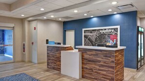 A hotel reception desk with a blue accent wall, a framed bicycle poster, and a digital screen. - Hampton Inn by Hilton Moab (Moab)