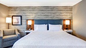 A hotel room with a large bed, two bedside tables with lamps, a chair, and a framed picture on the wall. - Hampton Inn by Hilton Moab (Moab)