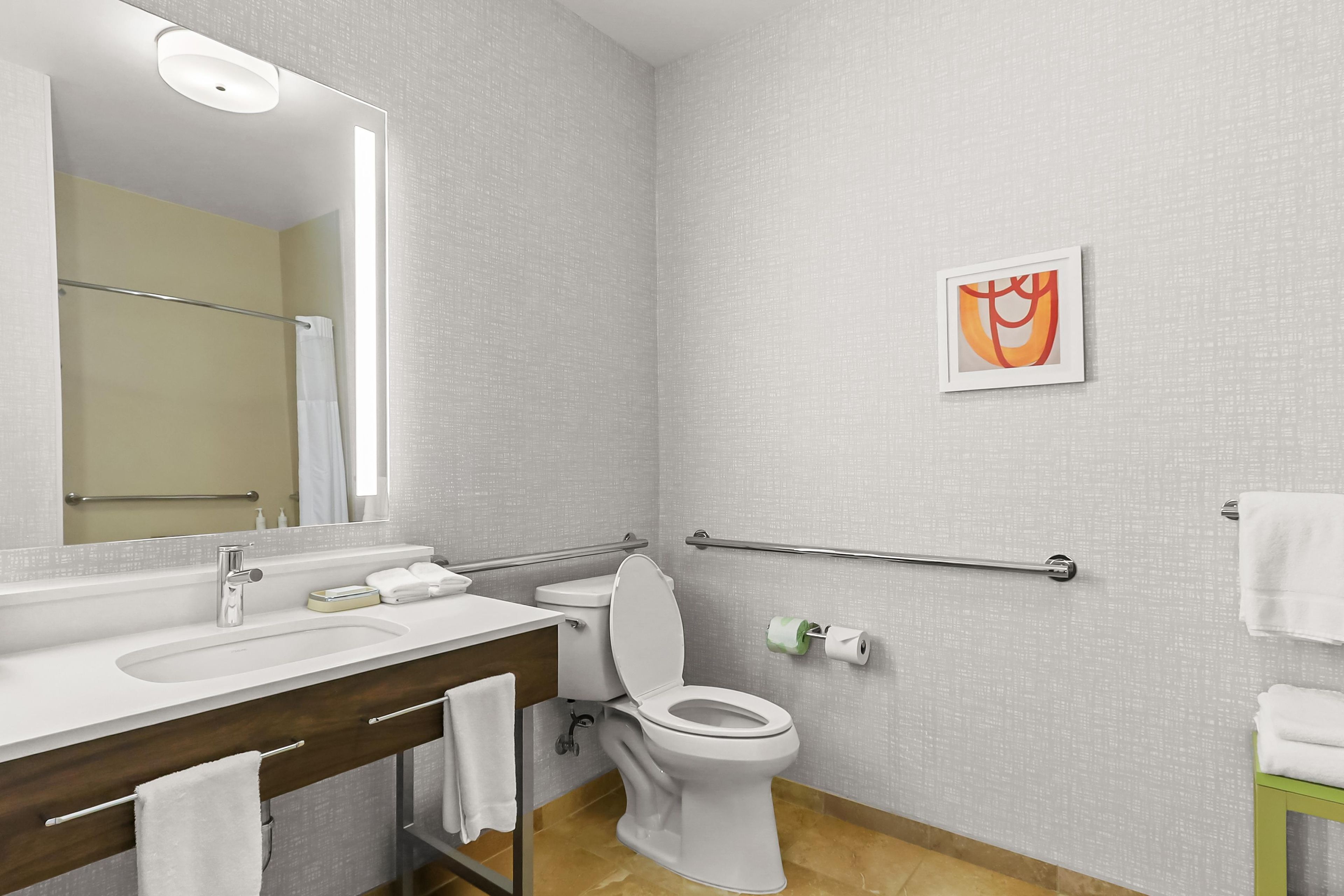 Een moderne badkamer met een wastafel, toilet en handgrepen.