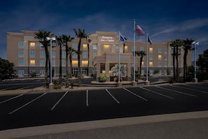 A hotel with a modern facade, palm trees, and a parking lot. - Hampton Inn & Suites El Paso West (El Paso)