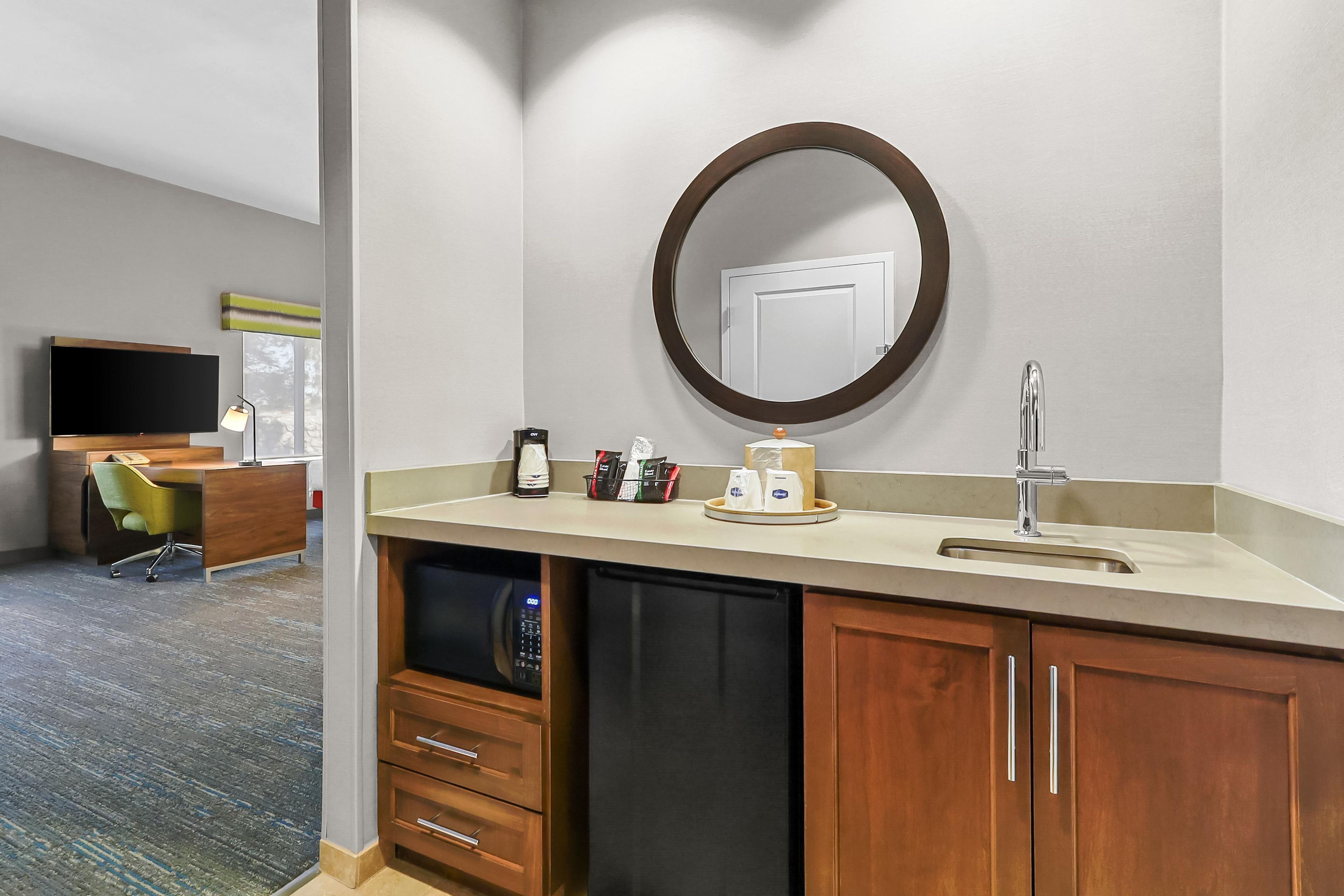 A hotel bathroom with a sink, mirror, and a coffee maker.
