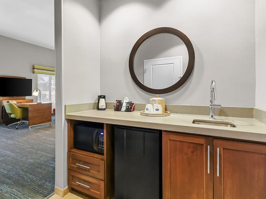 A hotel bathroom with a sink, mirror, and a coffee maker.