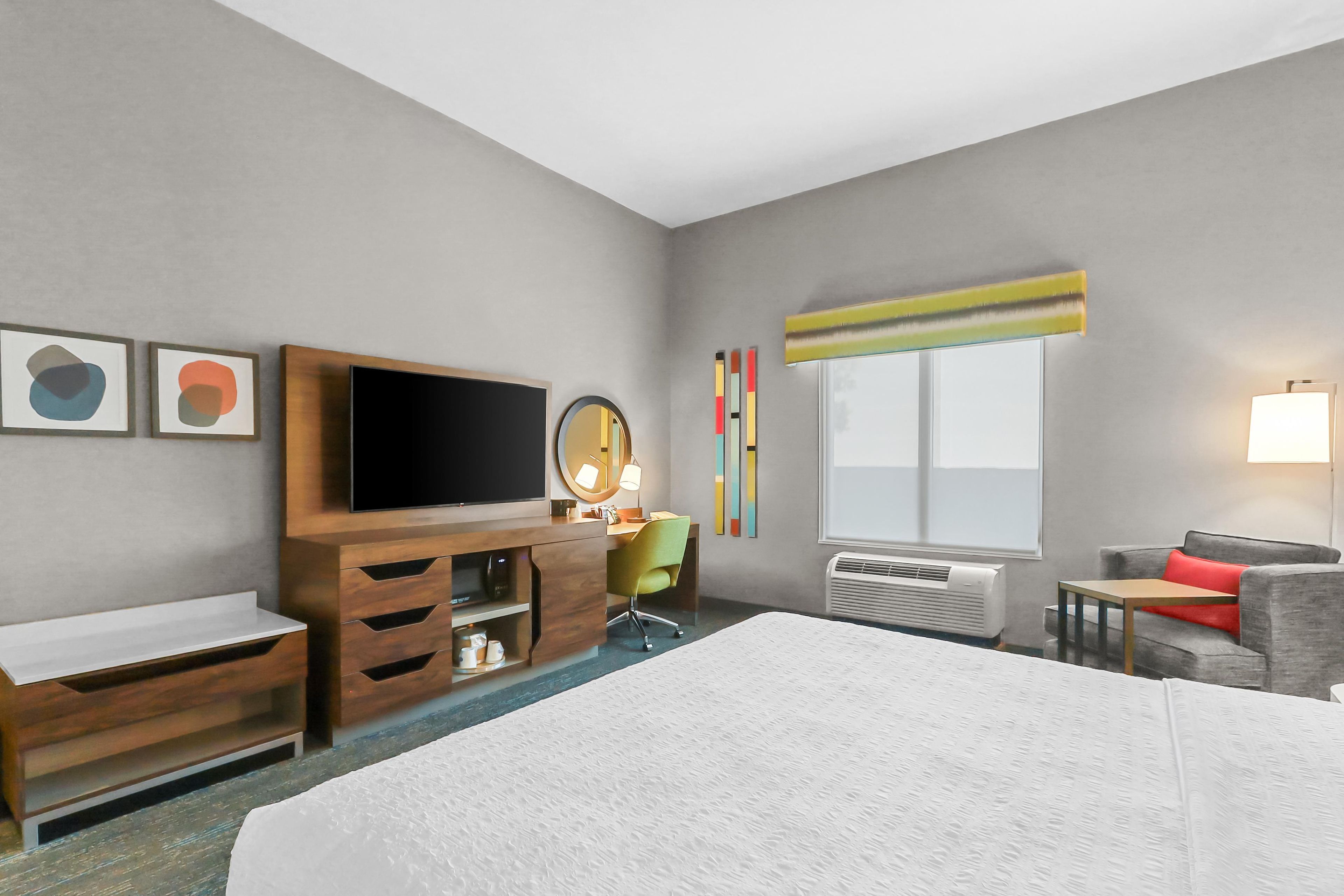 Een hotelkamer met een groot bed, een televisie, een bureau met stoel, een kleine tafel en een bank.