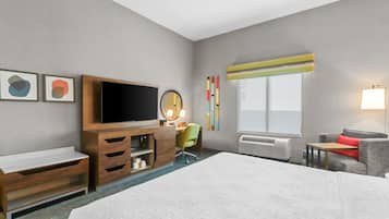 Une chambre d’hôtel avec un grand lit, une télévision, un bureau avec une chaise, une petite table et un canapé.