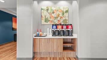 A reception area with a coffee station, a painting, and a blue wall.