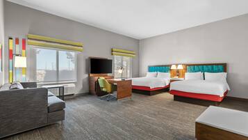 Une chambre d’hôtel avec un lit, un bureau, une chaise, une télévision et un canapé.