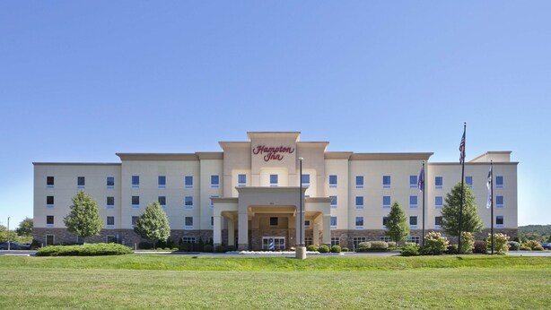 A Hampton Inn hotel with a central entrance, multiple floors, and a parking lot in front.